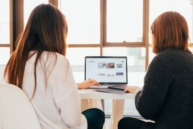 picature of two people working on one laptop